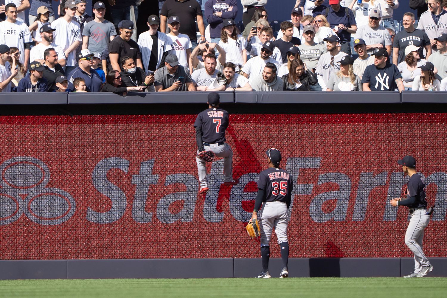 Apr 23, 2022; Bronx, New York, USA; Cleveland Guardians center fielder Myles Straw (7) climbs the fence to go after fans during the ninth inning against the New York Yankees at Yankee Stadium.
